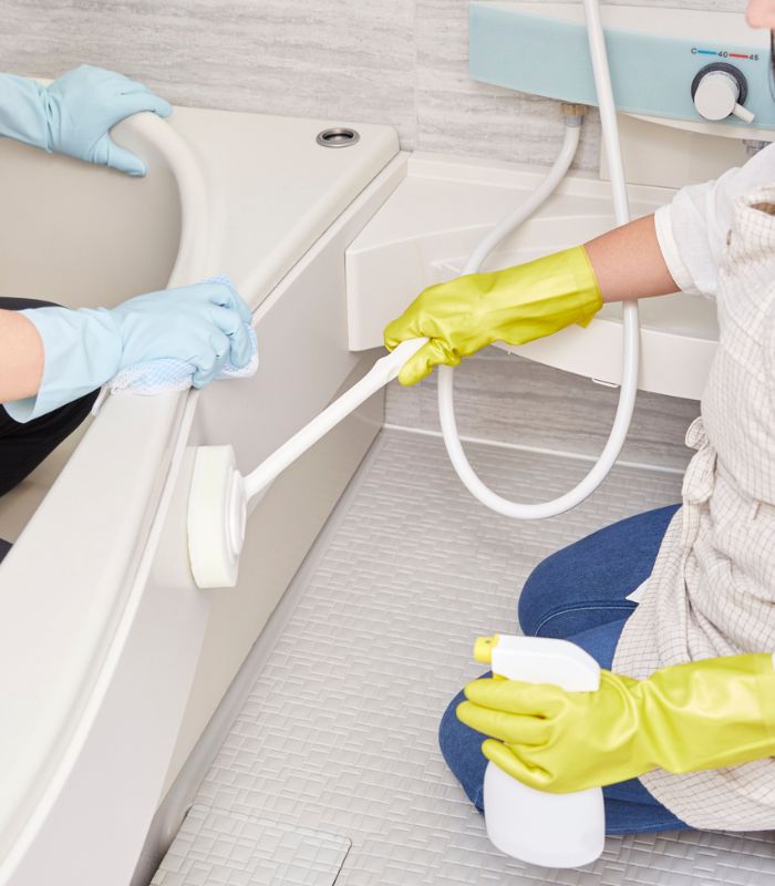 Cleaning team performing deep cleaning by scrubbing tiled floors and sanitizing surfaces in a bright home